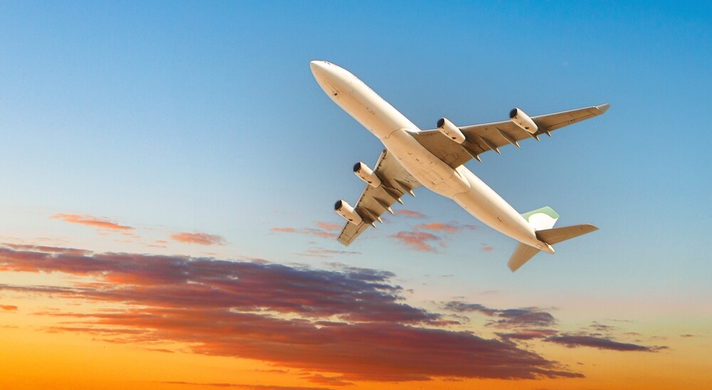 Big passenger plane ascending after takeoff in sunset sky.