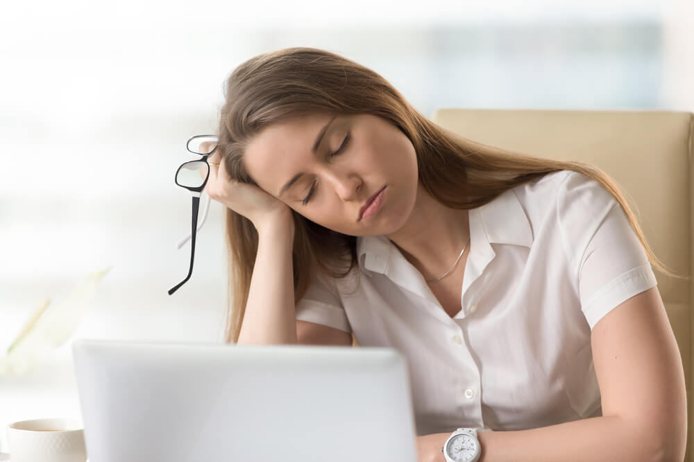 Bored sleepy businesswoman sitting half asleep at workplace.