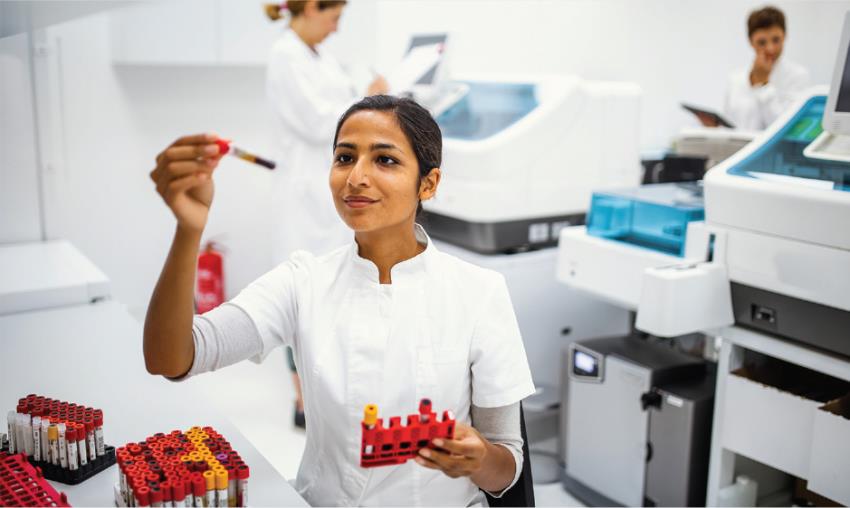 Female researcher in a lab holding up a lab tool and observing it