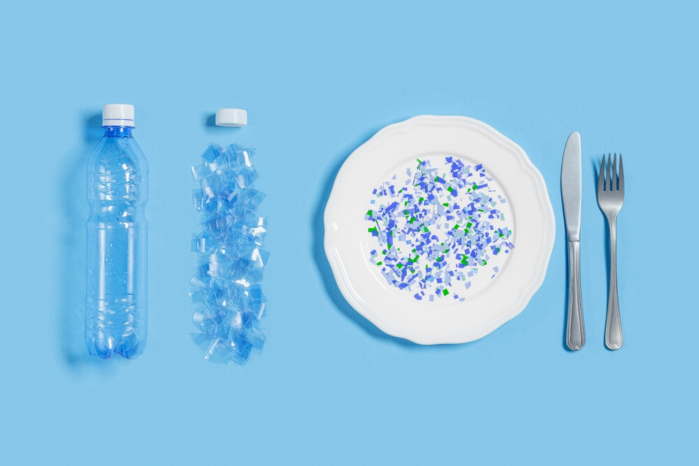 White plate full of microplastics on blue background with copy space. Plastic pollution concept, global ocean pollution ecology problem, microplastic particles in water and food, top view, flat lay