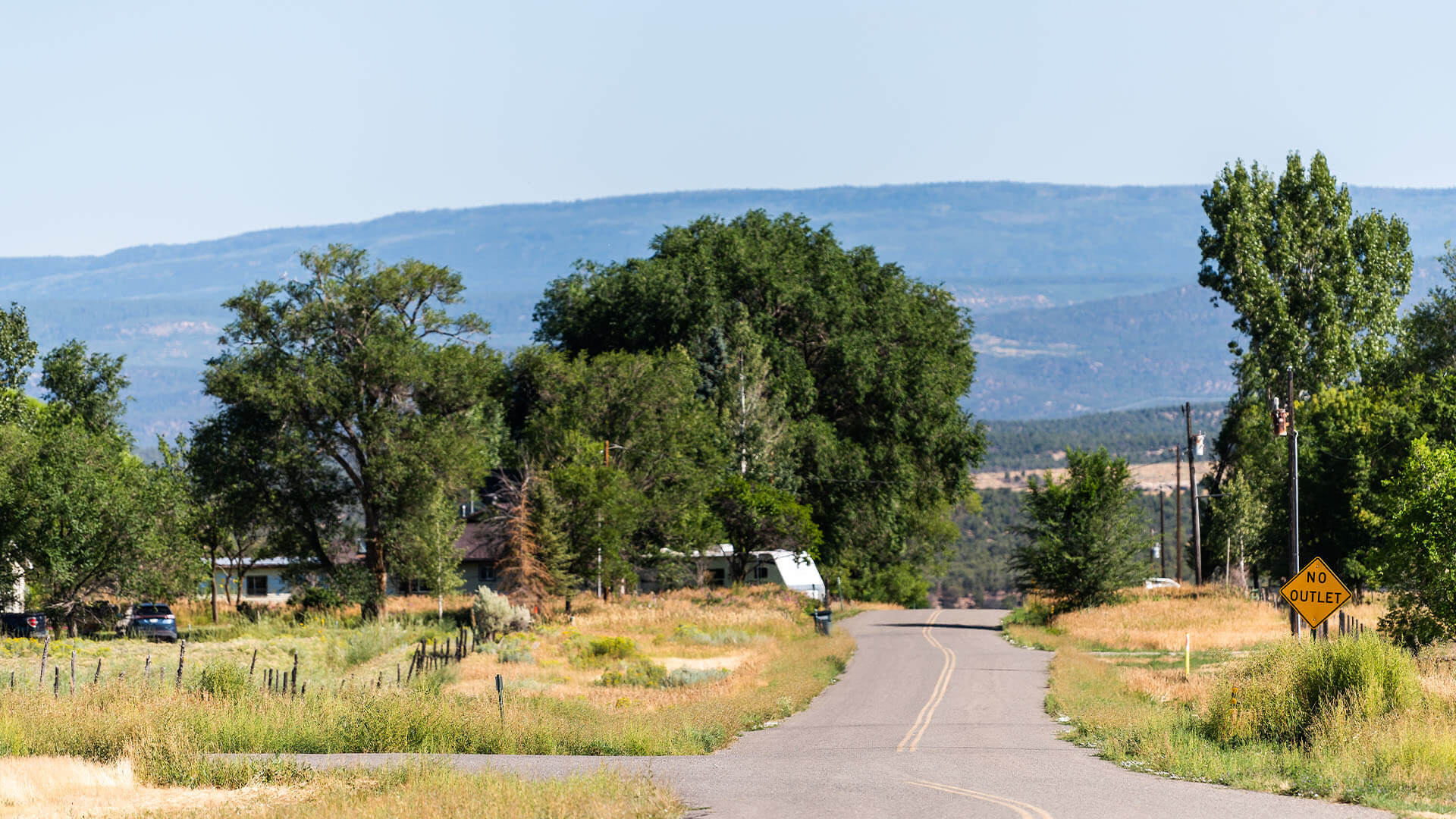 Empty road highway 145 through small town of Redvale, Colorado with nobody on summer sunny day with sky and mountain view