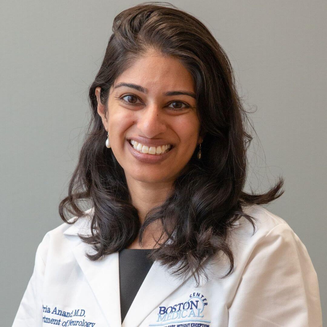 Headshot of neurologist and author Dr. Pria Anand wearing a white medical coat and smiling at the camera.