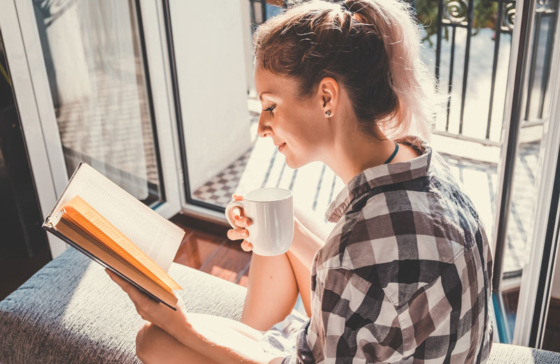 Woman reading a book by a window