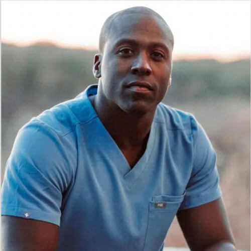Portrait of a physician wearing blue medical scrubs, seated outdoors
